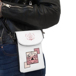 Könnte beinhalten: Eine weiße Umhängetasche mit einem rosa-weißen Design. Die Tasche zeigt einen Kristall, Monde und einen Würfel mit einer Bergszene im Inneren.