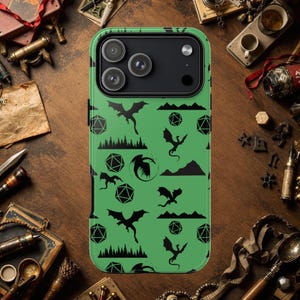 Puede incluir: Funda de teléfono verde con un patrón de dragón negro y geométrico. La funda presenta un diseño repetido de dragones, dados y siluetas de montañas. La funda del teléfono tiene un módulo de cámara con tres lentes.