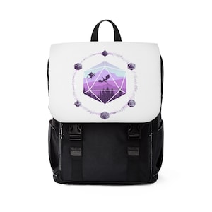 Puede incluir: Mochila negra con un panel frontal blanco que presenta un paisaje morado y rosa dentro de un dado morado y blanco con dos dragones negros volando por encima. El dado está rodeado por una corona de dados morados y blancos.