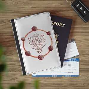 May include: White passport cover with a red dragon design and a circle of red dice around it. The cover has a black border and white stitching. The text "SPORT" is visible on a blue passport in the background.