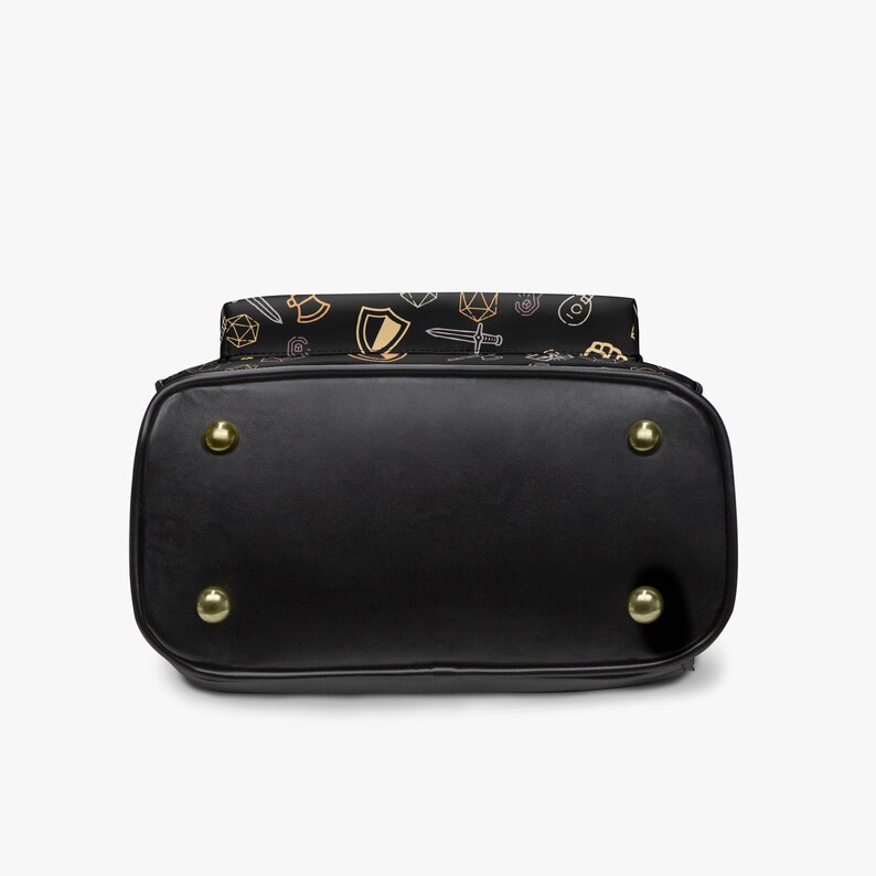 Mini PU leather backpack purse with fantasy RPG icons including dice, swords, shields, and spell symbols on a black background; front zipper pocket and top handle