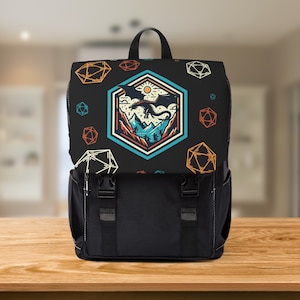 May include: Black backpack with a flap closure and two front buckles. The top flap features a design of a dragon, mountains, and a sun inside a hexagon, with colourful geometric shapes scattered around. The backpack has a top handle and a black body.