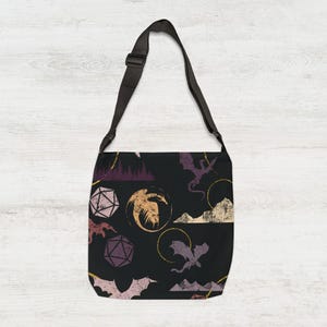 May include: Black tote bag featuring a repeating pattern of dragons, dice, and mountain silhouettes in purple, gold, and beige. It has a black adjustable shoulder strap.