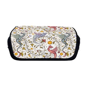 Könnte beinhalten: Eine weiße Reißverschlusstasche mit schwarzem Besatz. Die Tasche zeigt ein sich wiederholendes Muster aus Drachen und Ranken in Rot-, Blau-, Grün- und Gelbtönen.