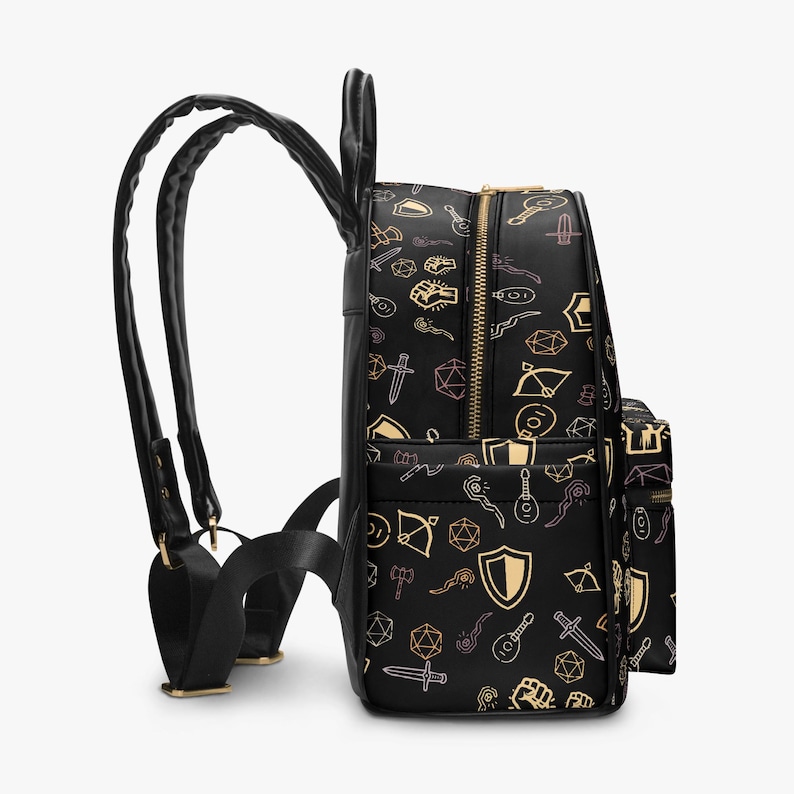 Mini PU leather backpack purse with fantasy RPG icons including dice, swords, shields, and spell symbols on a black background; front zipper pocket and top handle