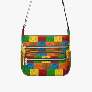 May include: A colorful crossbody bag with a geometric dice pattern. The bag features a black adjustable strap, multiple zippered compartments, and a vibrant patchwork design in red, blue, green, yellow, and orange.