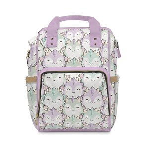 May include: A backpack featuring a repeating pattern of smiling cartoon dragons in shades of pastel purple and mint green. The bag includes a top handle, a front zippered pocket, and side pockets, all accented with solid light purple trim and zippers.