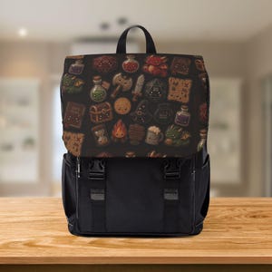May include: A black backpack featuring a flap with a repeating pattern of cartoon fantasy items including dragons, swords, treasure chests, potions, dice, maps, and books. The bag has two black plastic buckle closures on the front and a top handle.