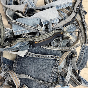 May include: A white ceramic mug with a black handle and the text "But First, Coffee" in a bold, black font. The mug is set against a blurred background, suggesting a cozy setting. The mug appears to be approximately 4 inches tall.