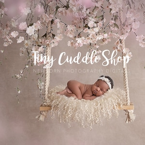 May include: A newborn baby girl sleeps peacefully on a swing decorated with white flowers. The swing is made of rope and wood and is hanging from a branch of a tree. The background is a soft pink color. The text "Tiny Cuddle Shop Newborn Photography Digitals" is visible in the image.
