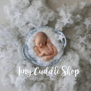 May include: A newborn baby sleeping in a blue basket surrounded by white fluffy clouds and white paper stars. The text "Tiny Cuddle Shop Newborn Photography Digitals" is at the bottom of the image.
