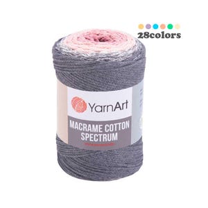 May include: A roll of YarnArt Macrame Cotton Spectrum yarn in a gray, white, and pink ombre colorway. The label reads "YarnArt Macrame Cotton Spectrum" and "www.yarnart.info".