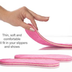 May include: Pink and white shoe insoles. The text on the image reads: "Thin, soft and comfortable. Will fit in your slippers and shows."