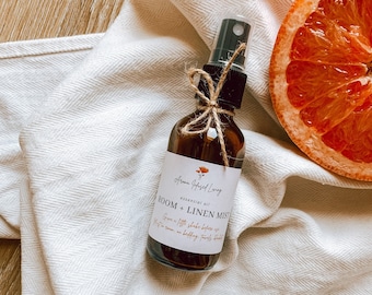 May include: A brown glass bottle with a black spray nozzle and a white label that reads "Aroma Infused Long essential oil ROOM + LINEN MIST Give a light shake before use Mist in room or on bedding, fresh laundry"
