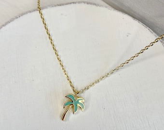May include: A gold chain necklace with a small, green enamel palm tree pendant.