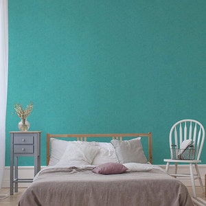 Può includere: Una scena di camera da letto con un letto con struttura in legno, coperto da un piumino marrone e cuscini bianchi. Un comodino grigio con un vaso di fiori e una sedia bianca sono presenti. Il muro è di colore turchese.