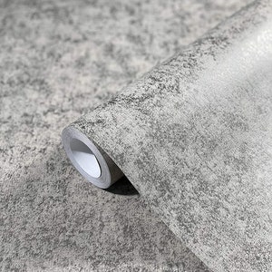 Op de afbeelding: Een rol grijze, gestructureerde behang met een subtiel gespikkeld patroon. Het behang heeft een licht ruwe, bijna betonachtige afwerking.