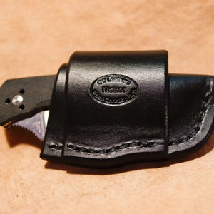 May include: A black leather knife sheath with a stitched edge and a circular embossed logo that reads "CG Leather Maker".