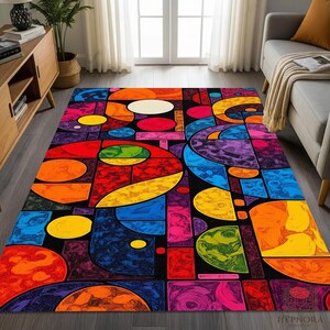 Op de afbeelding: Een kleurrijk rechthoekig vloerkleed met een abstract geometrisch ontwerp. Het kleed heeft een zwarte achtergrond met vormen in rood, oranje, geel, blauw, groen en paars. Het kleed is gemaakt van een zacht materiaal.