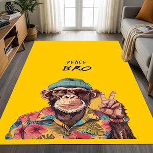 Puede incluir: Una alfombra rectangular amarilla con un mono de dibujos animados que lleva gafas de sol, un gorro azul y una camisa floral. El mono hace el signo de la paz. Las palabras "PEACE BRO" están impresas encima de la cabeza del mono.