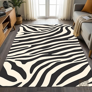 Puede incluir: Una alfombra rectangular con un llamativo diseño de rayas de cebra en negro y crema. La alfombra está colocada sobre un suelo de madera oscura en un salón, con un sofá y un mueble de madera en el fondo. El diseño de la alfombra añade un contraste llamativo.