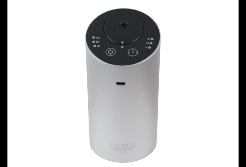 May include: A silver and black electric diffuser with a digital display and a knob to adjust the mist output. The diffuser has a power button and a timer button. The diffuser has a small hole on the side for charging.