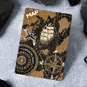 May include: A black and gold map card with a compass, a ship, and a seagull. The card has the word "MAP" printed in gold letters at the top.