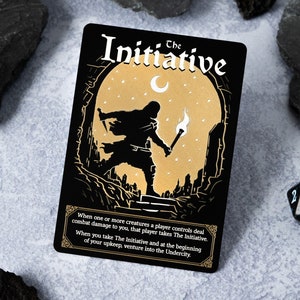 Puede incluir: Una carta negra con detalles dorados presenta una ilustración de una persona que sostiene una antorcha y camina por una cueva oscura. El texto "The Initiative" está escrito en una fuente estilizada en la parte superior de la carta. La carta también incluye texto que describe las reglas del juego.