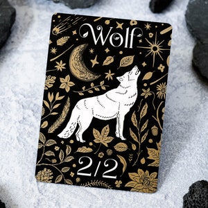 May include: A black card with a white wolf howling at the moon. The card has a gold background with a floral pattern and the text "Wolf" and "2/2".