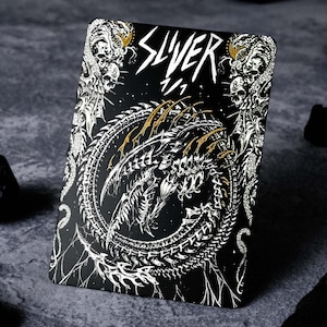 May include: A black playing card with a white and gold design. The card features a skeletal dragon with the word "SLIVER" in gold lettering.