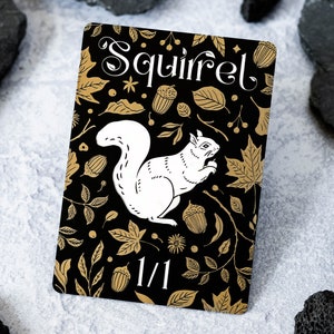 May include: A black card with gold accents featuring a white squirrel illustration and the text "Squirrel 1/1". The card has a black background with a gold floral pattern.