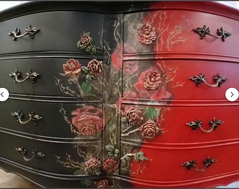 May include: A two-toned dresser with a black and red finish. The black side features rose and thorn accents, while the red side has rose embellishments. Each drawer has ornate, dark metal handles.