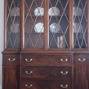 May include: A dark wood hutch with glass doors and drawers. The glass doors have a diamond pattern and the drawers have brass handles.