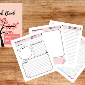 Könnte beinhalten: Ein rosa-schwarzer Laborgelenkdeckel mit einem Baum und Herzen. Der Deckel trägt den Titel "Lab Book". Die Innenseiten des Buches sind leer und mit Linien zum Schreiben versehen. Es gibt auch Seiten mit einem Gittermuster.