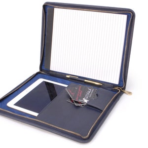 May include: A navy blue leather zipped portfolio with a notepad, pen, and tablet inside. The portfolio has a pocket for business cards and a zipped closure.