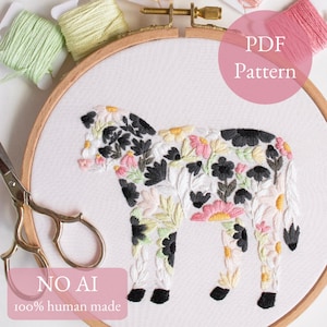 Könnte beinhalten: Ein Stickrahmen mit weißem Stoff, auf dem eine Kuhsilhouette in schwarzen, rosafarbenen, gelben und grünen Blumenmustern gestickt ist. Das Bild enthält den Text PDF Pattern und NO AI 100% human made sowie Stickgarn und eine Schere.