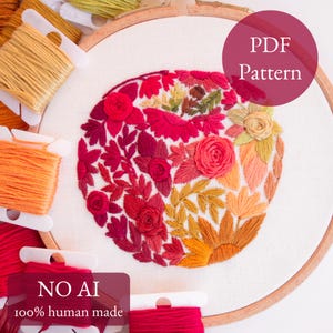 Puede incluir: Un bastidor de bordado con un diseño floral circular cosido con hilos en tonos rojo, rosa, naranja y amarillo. El diseño presenta varios patrones de flores y hojas. Varias bobinas de hilo de bordar en colores a juego rodean el bastidor. El texto en la imagen dice "PDF Pattern" y "NO AI 100% human made".