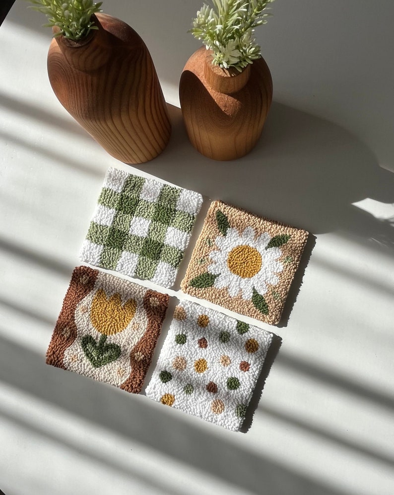 Coaster made with punch needle technique, with a floral pattern on it, dominated by green and brown tones