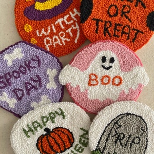 May include: Six round, colorful, felt-like Halloween-themed decorations. The decorations feature a witch hat, a pumpkin, a ghost, a tombstone, a skeleton, and the words "Trick or Treat".