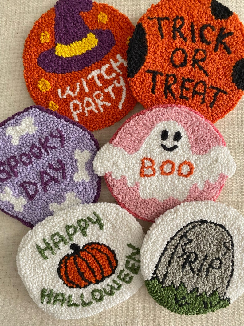 May include: Six round, colorful, felt-like Halloween-themed decorations. The decorations feature a witch hat, a pumpkin, a ghost, a tombstone, a skeleton, and the words "Trick or Treat".
