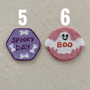 May include: Two handmade felt ornaments, one purple with the text "Spooky Day" and the other pink with a white ghost and the text "Boo".