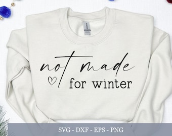 May include: Cream-colored sweatshirt with the phrase "not made for winter" in black script. A small heart is next to the word "not". The sweatshirt is surrounded by holiday decorations, including a candy cane and berries.