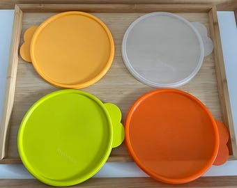 May include: Four plastic lids in different colours: yellow, green, white and orange. The lids have a flower-shaped design around the edge.
