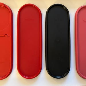 May include: Four oval-shaped plastic containers with lids. Two are red, one is black, and one is pink. The lids are all closed.