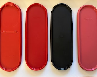 May include: Four oval-shaped plastic containers with lids. Two are red, one is black, and one is pink. The lids are all closed.