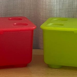 Könnte beinhalten: Zwei Plastik-Aufbewahrungsbehälter mit Deckeln. Einer ist rot und der andere grün.
