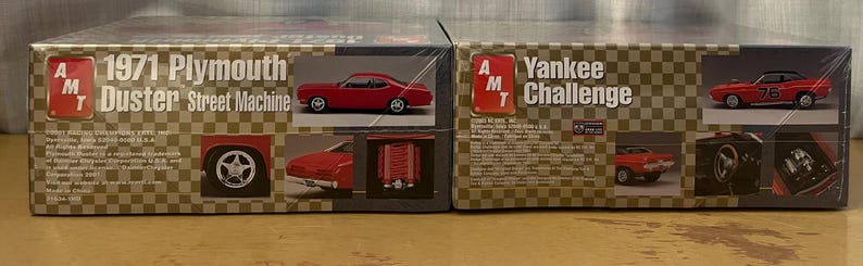 Op de afbeelding: Twee modelbouwsets voor auto's, een is een 1971 Plymouth Duster Street Machine en de andere is een Yankee Challenge. Beide sets zijn van AMT.