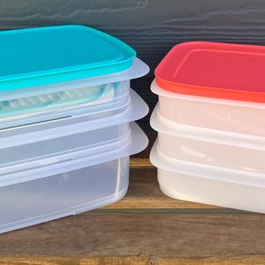 Peut inclure: Deux ensembles de contenants de rangement en plastique transparent avec couvercles. Un ensemble a un couvercle turquoise et l'autre un couvercle rouge.