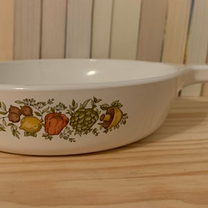May include: White ceramic baking dish with a handle. The dish features a floral design with green leaves and colourful vegetables.
