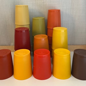 May include: A set of 10 colorful plastic cups in various shades of red, orange, yellow, and brown. The cups are stacked in a pyramid shape.